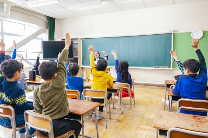 授業中に元気よく挙手する小学生たち