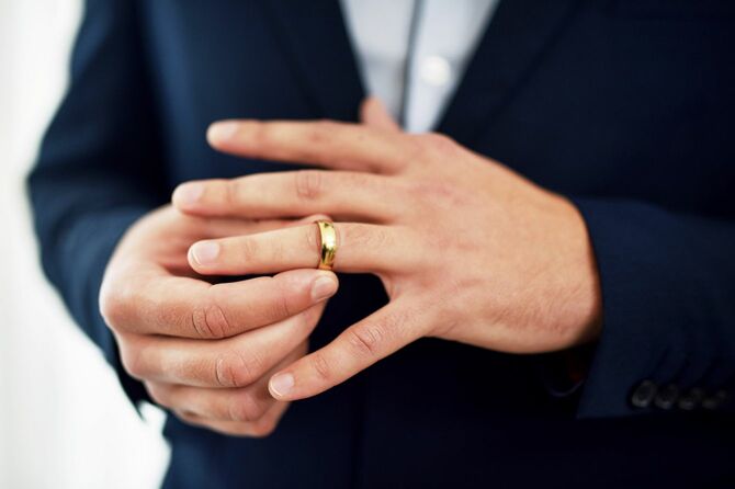 結婚指輪を外している男性の手元