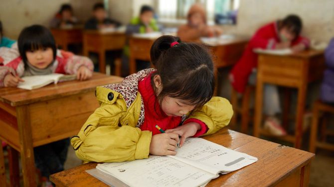 中国の学校の教室で、書き取りをする少女