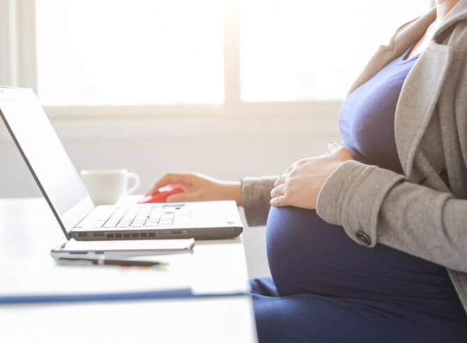 妊娠後期の女性がノートパソコンを使用して仕事中