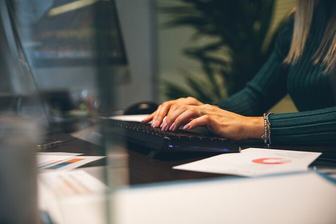 職場の女性がオフィスでコンピュータキーボードに入力します。