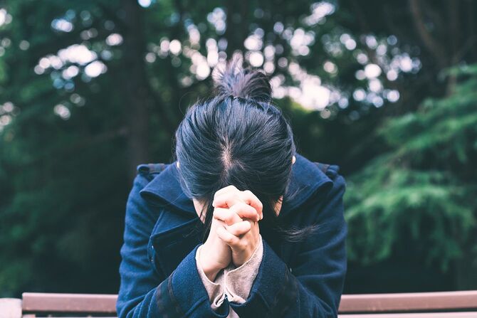 外で祈る女性。
