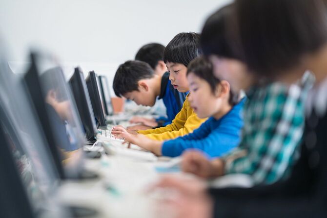 学校でコンピュータを使うことを学ぶ小学生