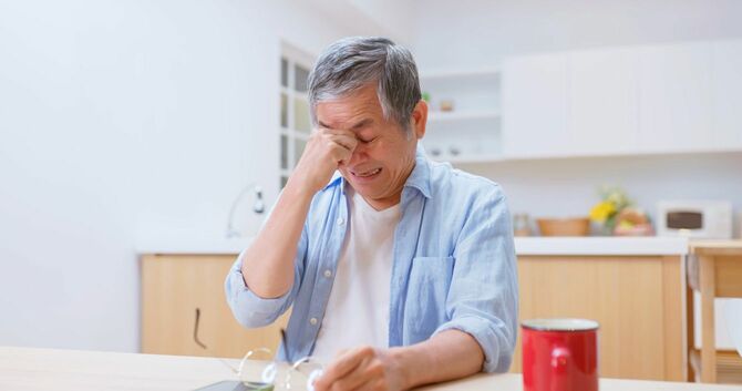 目頭をおさえる高齢者