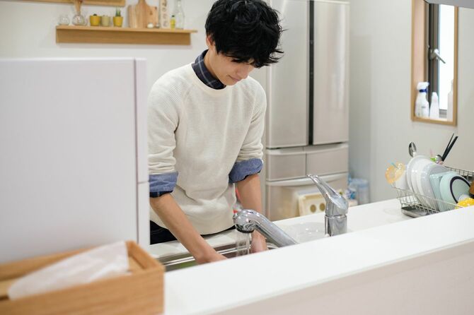 キッチンで皿を洗う男性