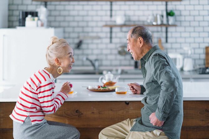 家でお茶を飲みながら話をする高齢夫婦