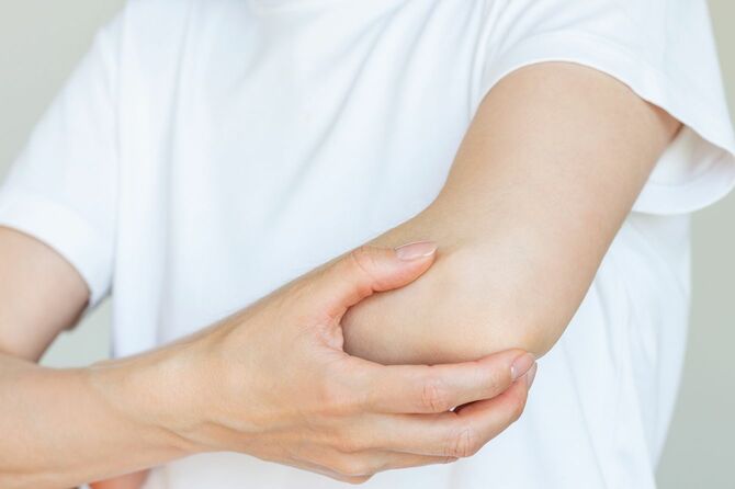 肘関節を握り、痛みの程度を確認している女性