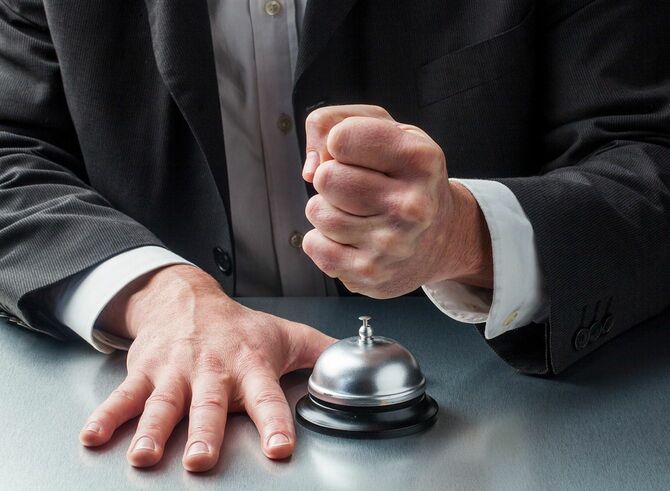 呼び出しベルとこぶしを握る男性