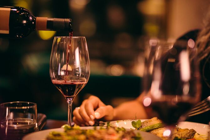 ディナーの席でグラスに注がれる赤ワイン