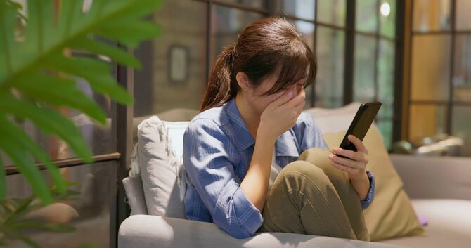 スマホを見て悲しくて落ち込んでいる女性