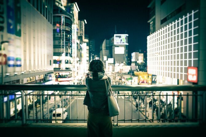 歩道橋から町の夜景を眺める女性