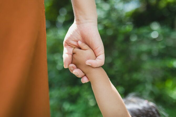 息子の手をひいて歩く母親