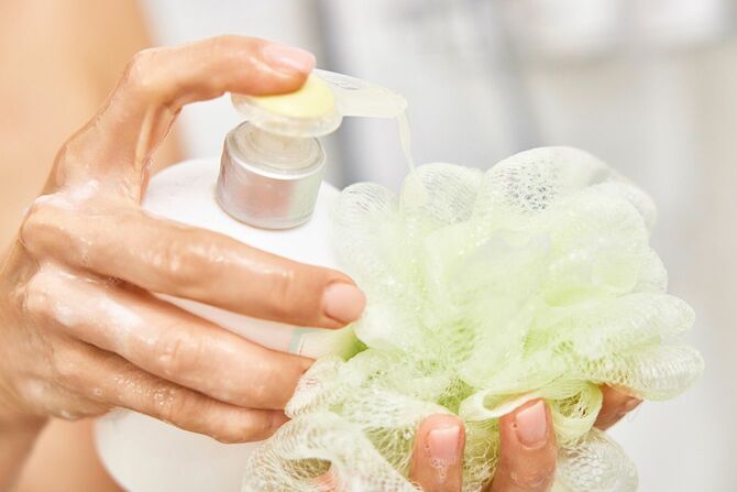 ボトルから液体石鹸をスポンジに注ぐ女性の手