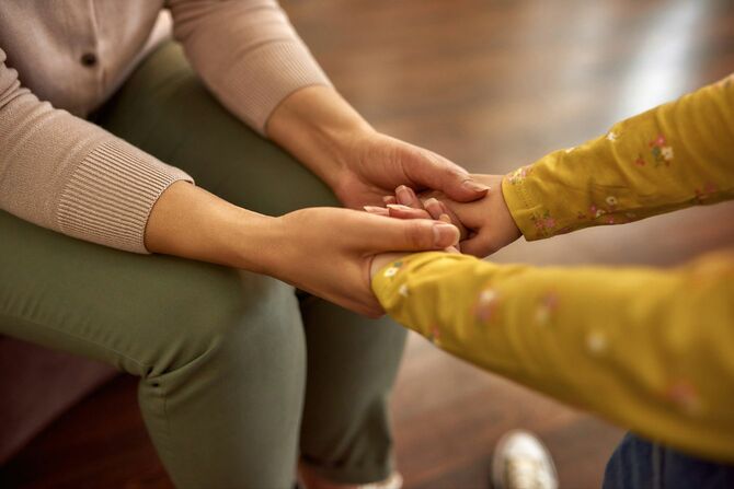 女性の手で子供の手をとる