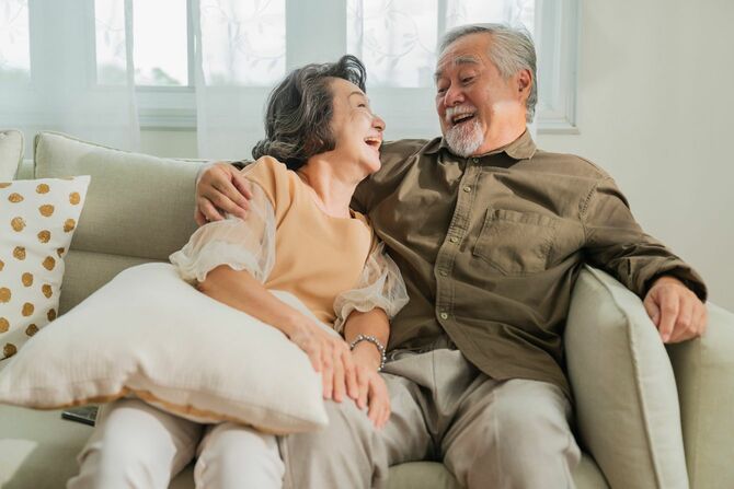 リビングルームのソファで一緒に過ごす笑顔の老夫婦