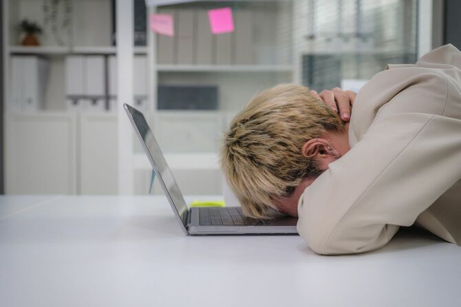 オフィスでノートパソコンに突っ伏している人