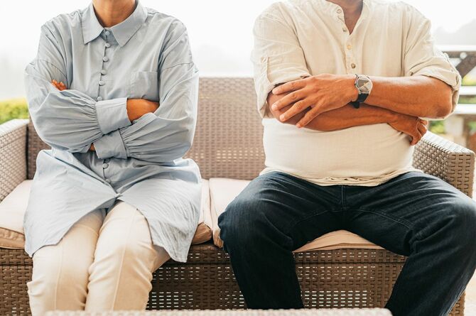 隣り合って座っているのに、二人とも腕を組んで会話を拒否しているシニアカップル