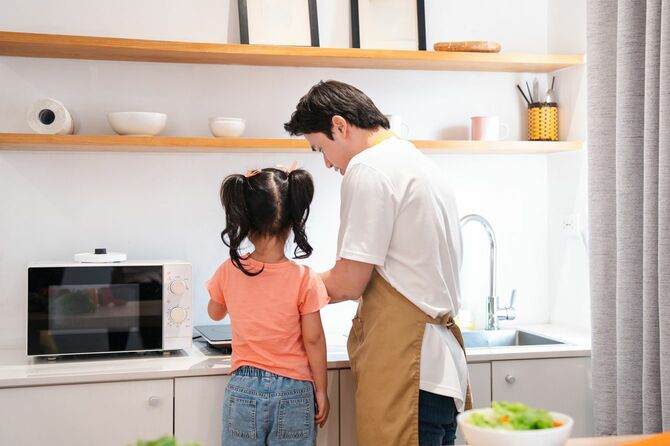 幼い娘と料理をする父親