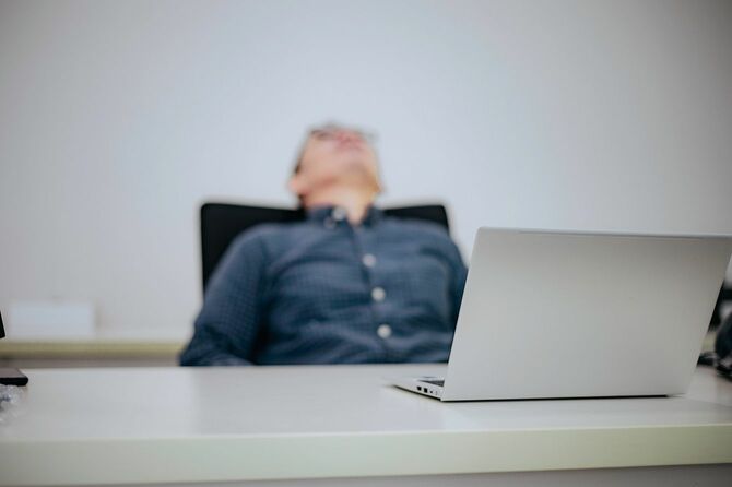 椅子にもたれかかって寝る男性