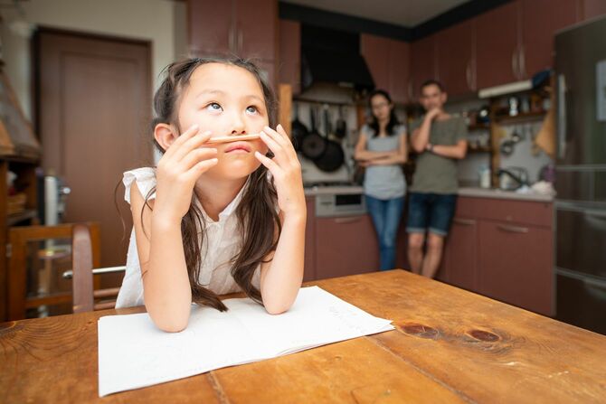 鉛筆を鼻の下にあてて、自由に試行している少女とそれを見守る両親