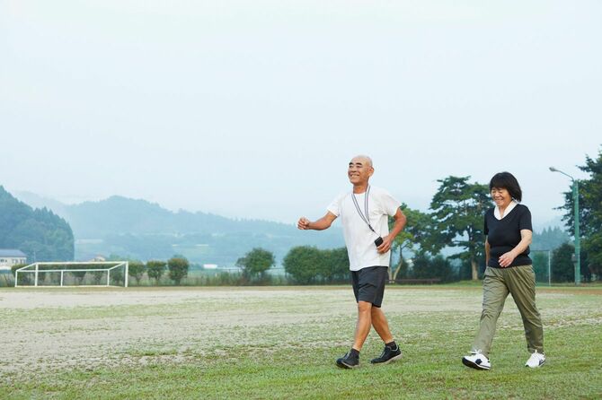 グラウンドを歩くシニア男性と女性