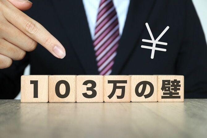 103万円の壁と書かれた木製ブロックを指さす人