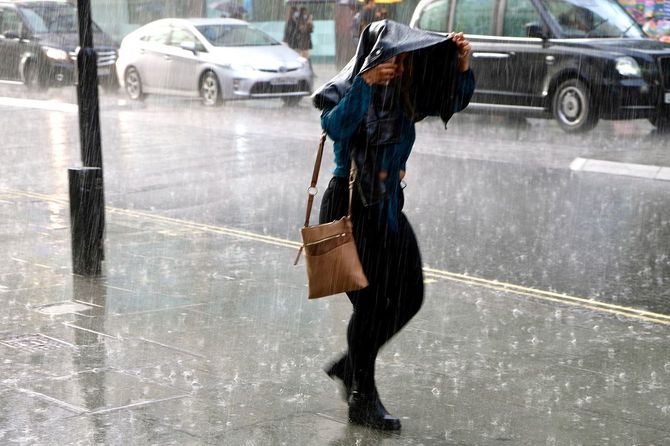 ロンドンのオックスフォードストリートで大雨の中を歩く女性