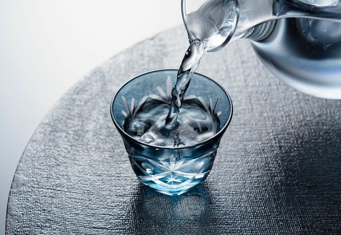 切子の冷酒杯に冷酒を注いでいる手元