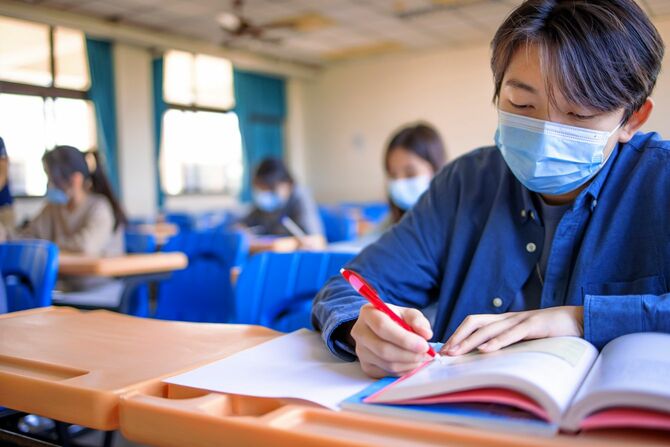 保護マスクを着用し、教室で勉強する学生