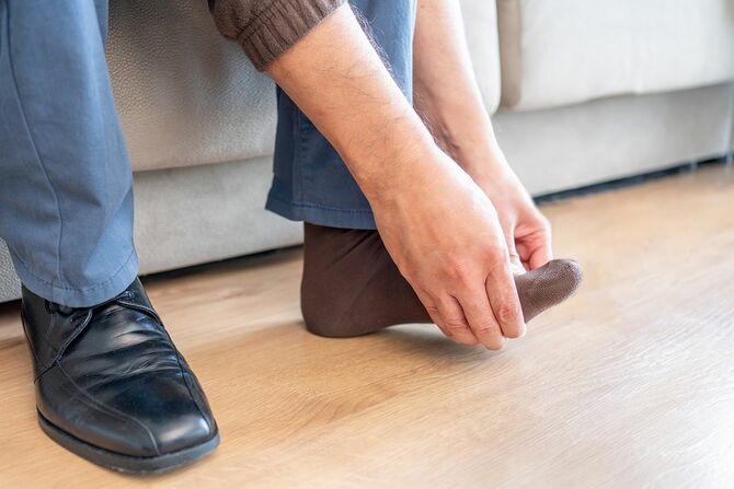 男が手で足を触れている
