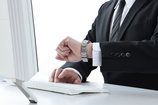 デスクワーク中に時間を確認するビジネスマン