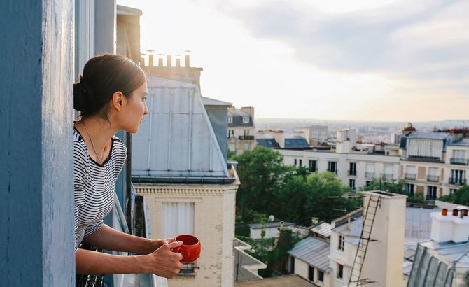 パリのアパートメントからの眺めを楽しむ若い女性