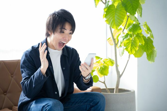 スマホを見て驚く20代の男性