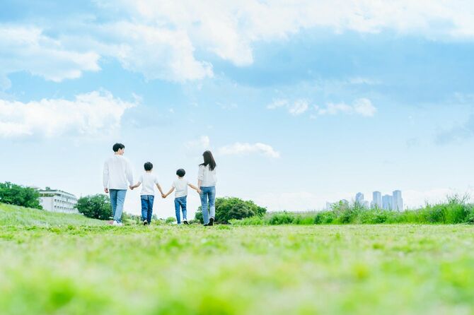青空を背景に草原を歩く家族