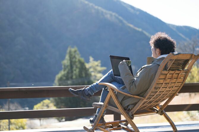 山でコーヒーを飲みながらリモートで作業する男性のクローズアップ