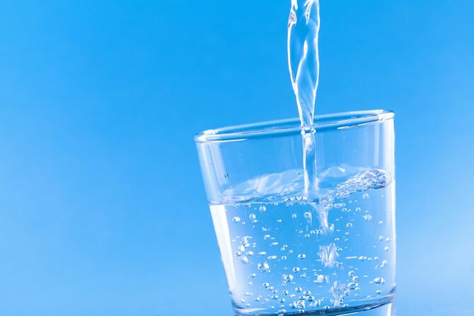 青い背景にガラスに注ぐ水を飲む