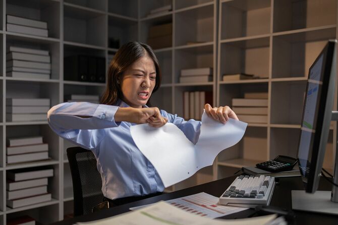 仕事中に書類を破く女性