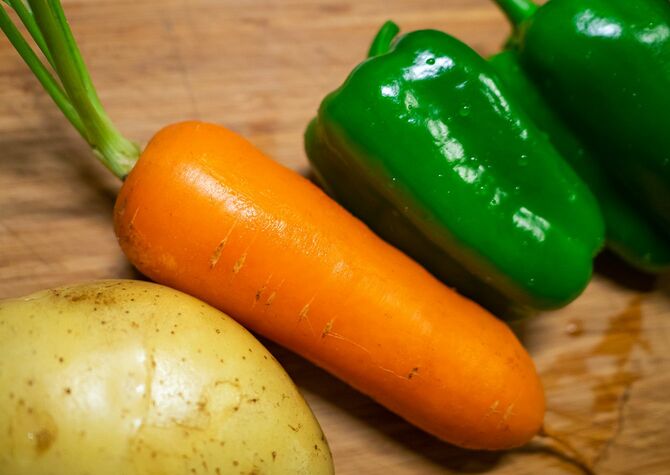 まな板の上のにんじんポテトとピーマン