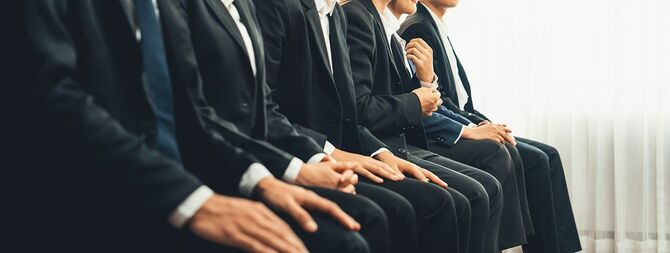 フォーマルなスーツを着た求職者が面接に列をなす