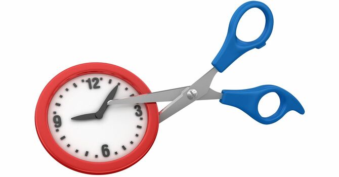 ミニチュアの時計をハサミで切ろうとしているイメージ写真