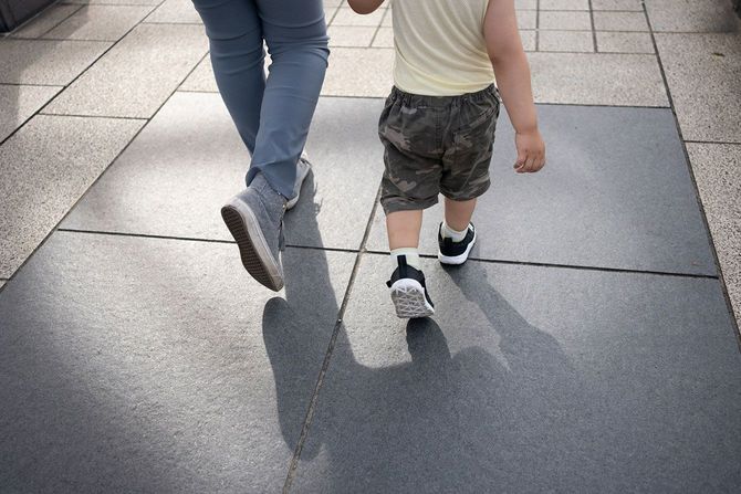 手をつないで歩く母子の後ろ姿