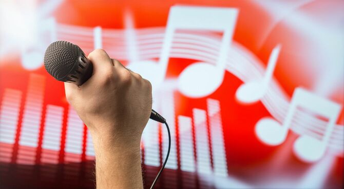 カラオケの画面の前でマイクを握る手元