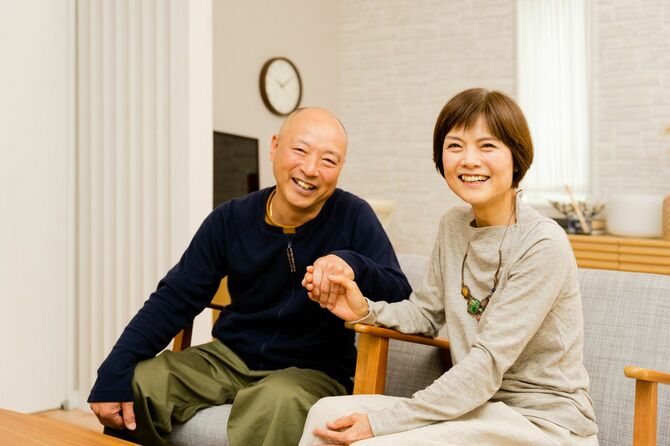 部屋の中で手をつないで笑顔を見せる熟年カップル