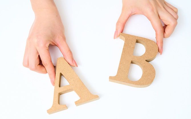 木製のアルファベットブロックの「A」と「B」を持つ手