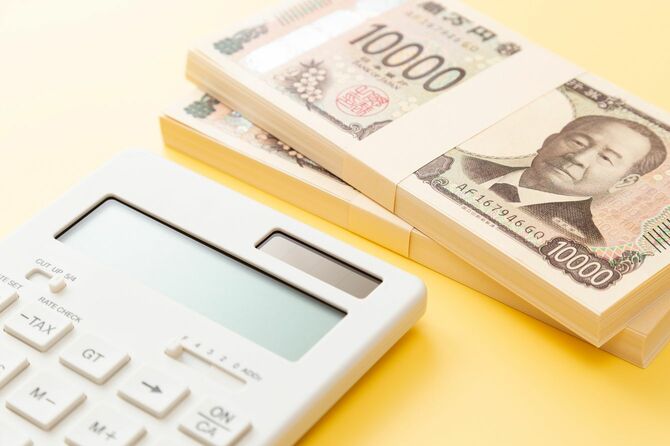 黄色の背景に一万円札の山と電卓