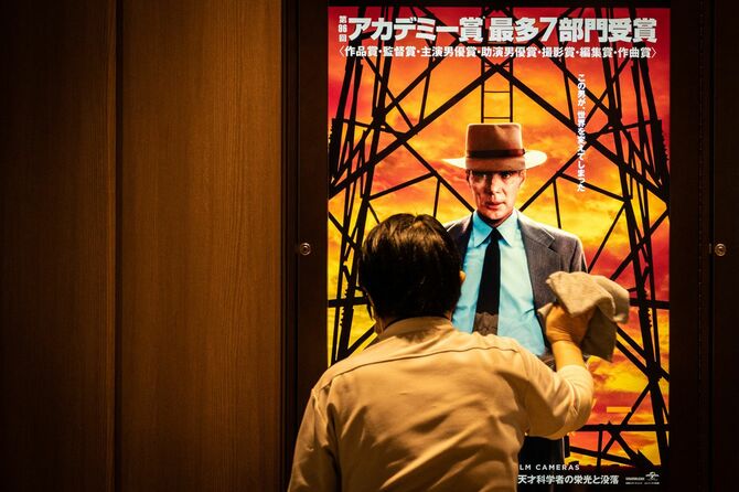 映画「オッペンハイマー」のポスターが映し出されたスクリーンを清掃する作業員＝2024年3月29日、東京都内