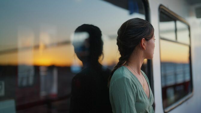 フェリーで旅行する若い女性と夕焼け