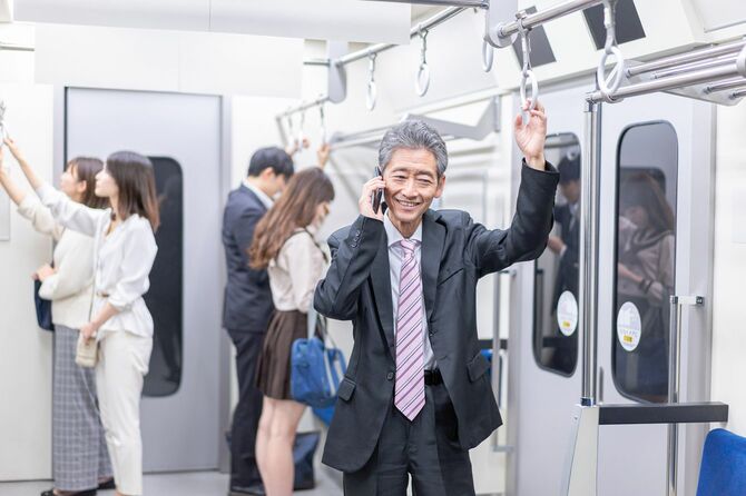 電車の中で話すビジネスマン