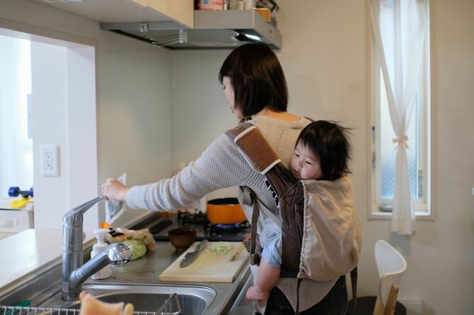 母親が台所で赤ちゃんと一緒に料理