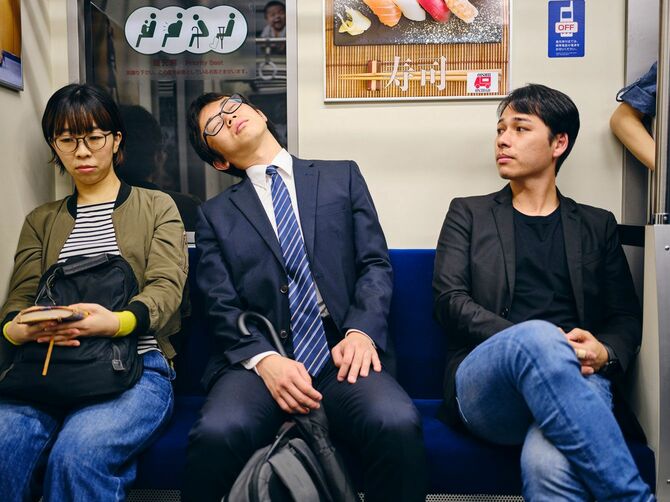 地下鉄の優先席で眠るビジネスマン